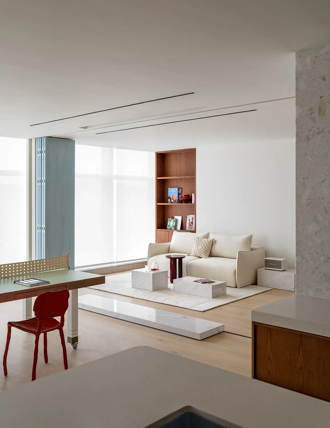 Modern minimalist living room featuring a white couch, marble coffee tables, and a marble tile floor.
