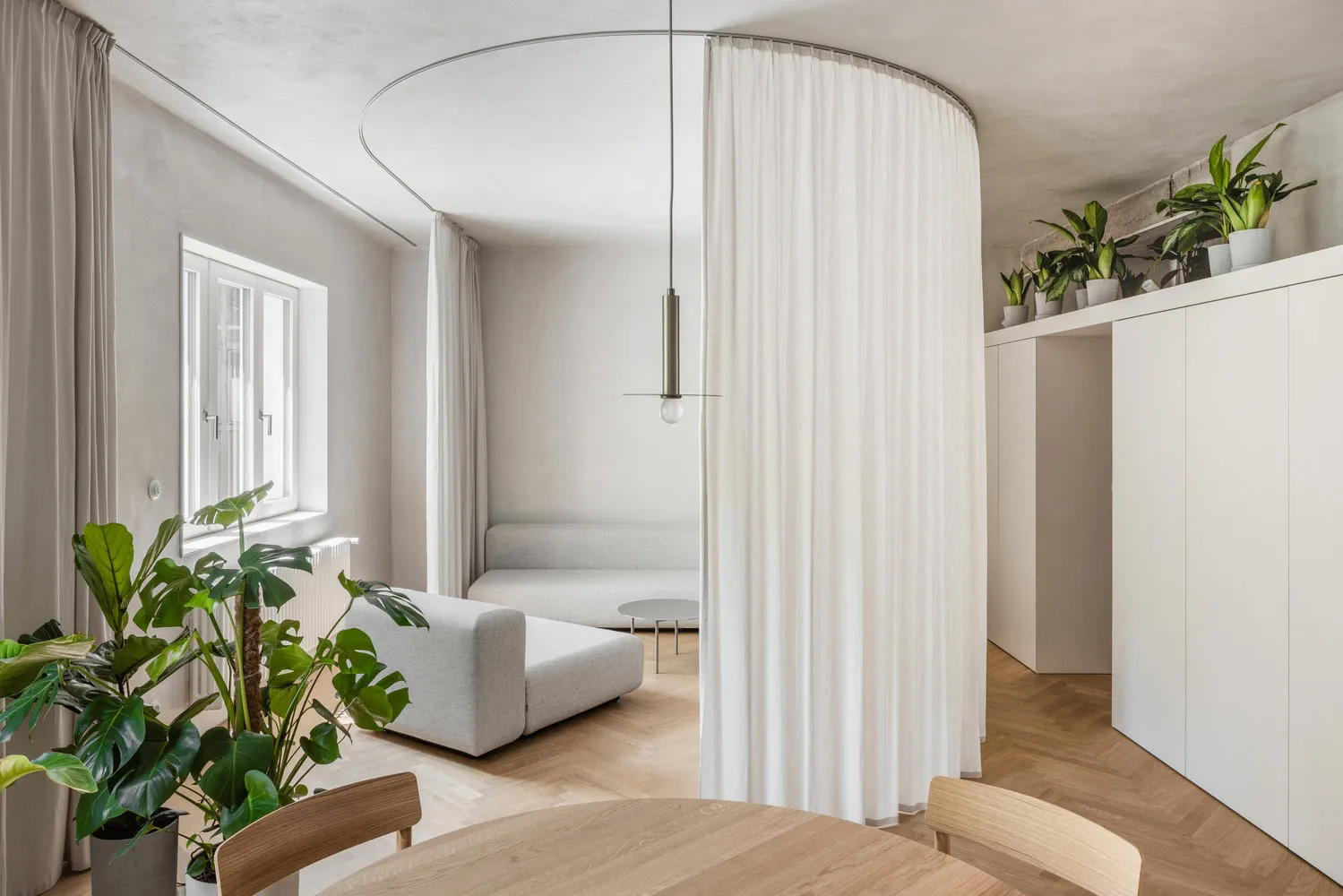 A minimalist living room with white cloth furniture and white curtains.