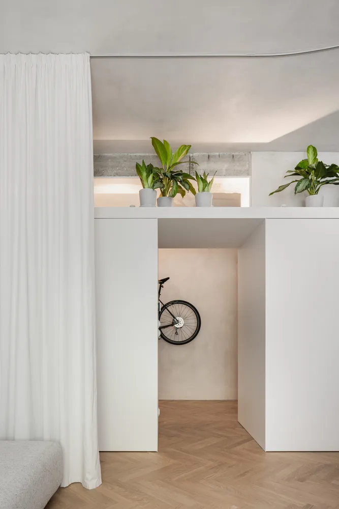 A minimalist interior design featuring white cabinets, concrete walls, and potted plants.