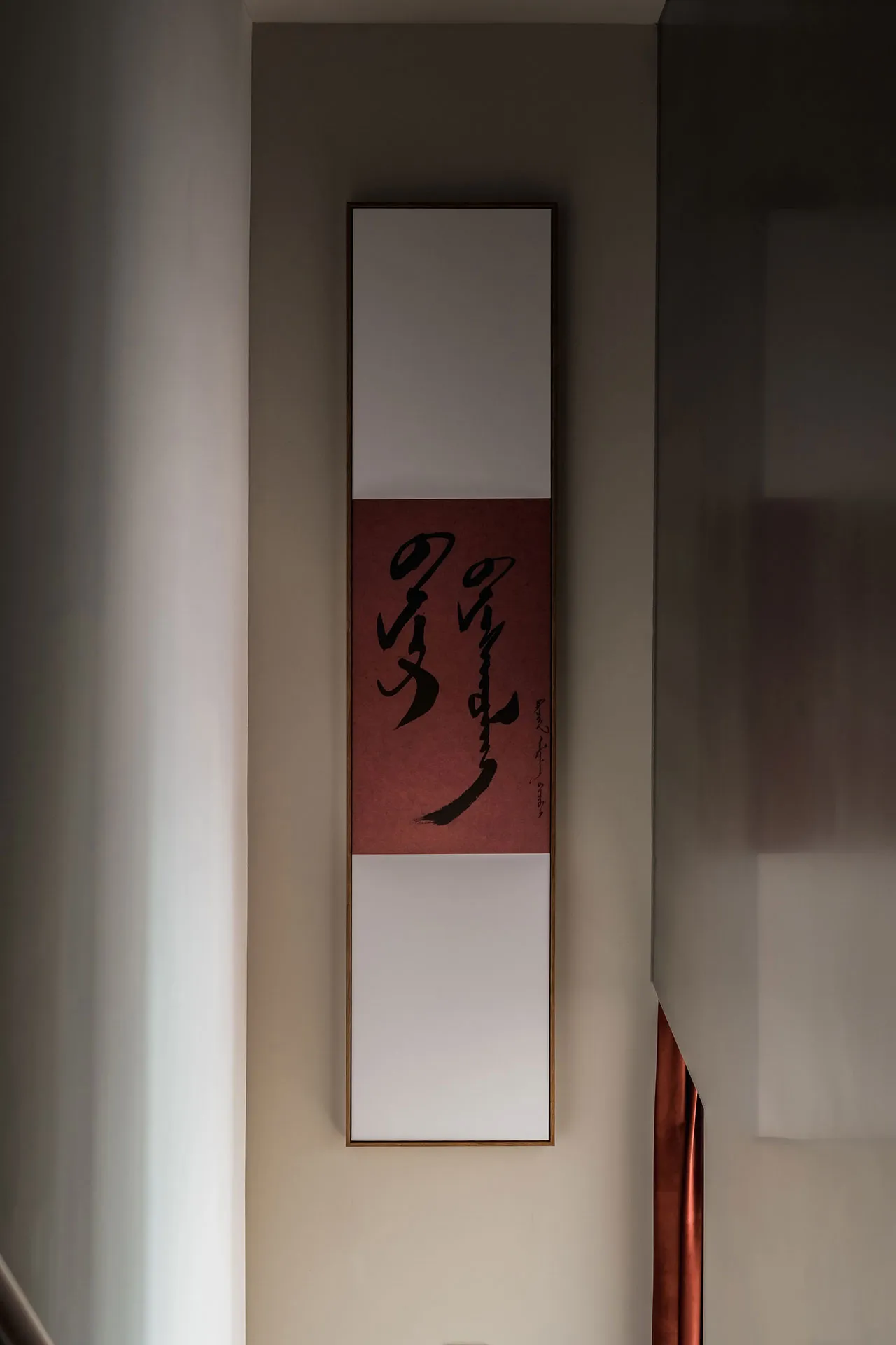 一幅現代風格的書法卷軸,紅底黑字,懸掛在淺色牆面上。