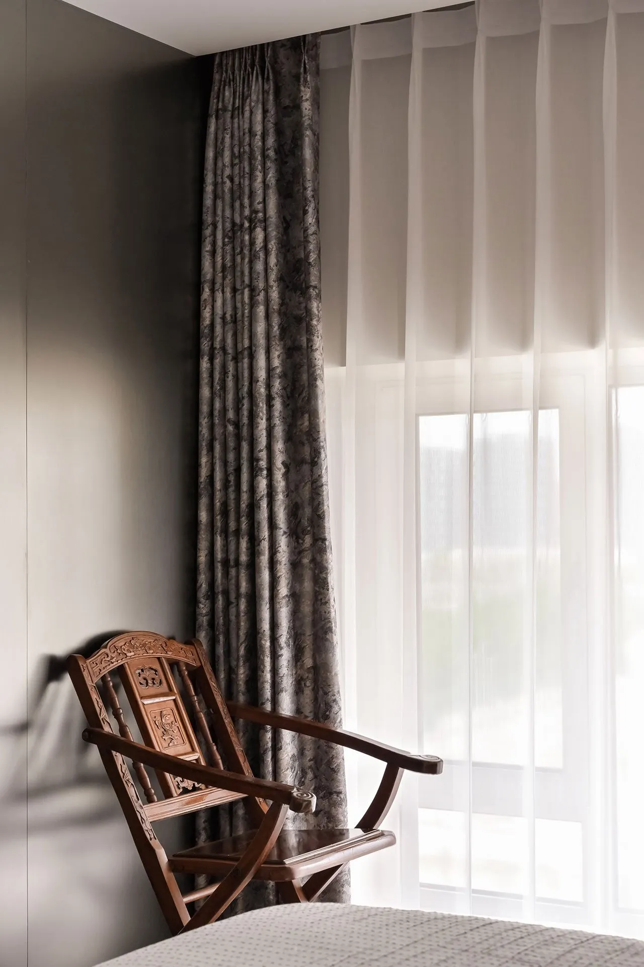 A minimalist bedroom featuring a wooden chair by a window.