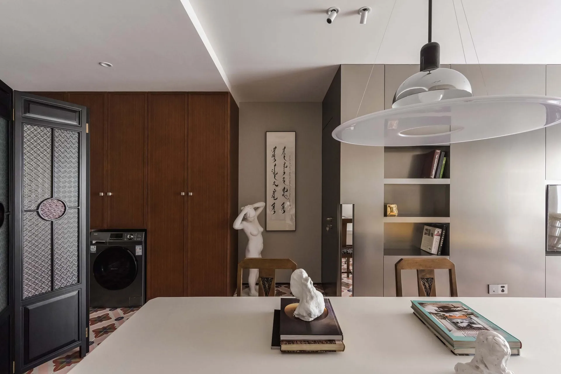 A modern residential kitchen with minimalist design elements, including wooden cabinets, metal accents, and concrete countert