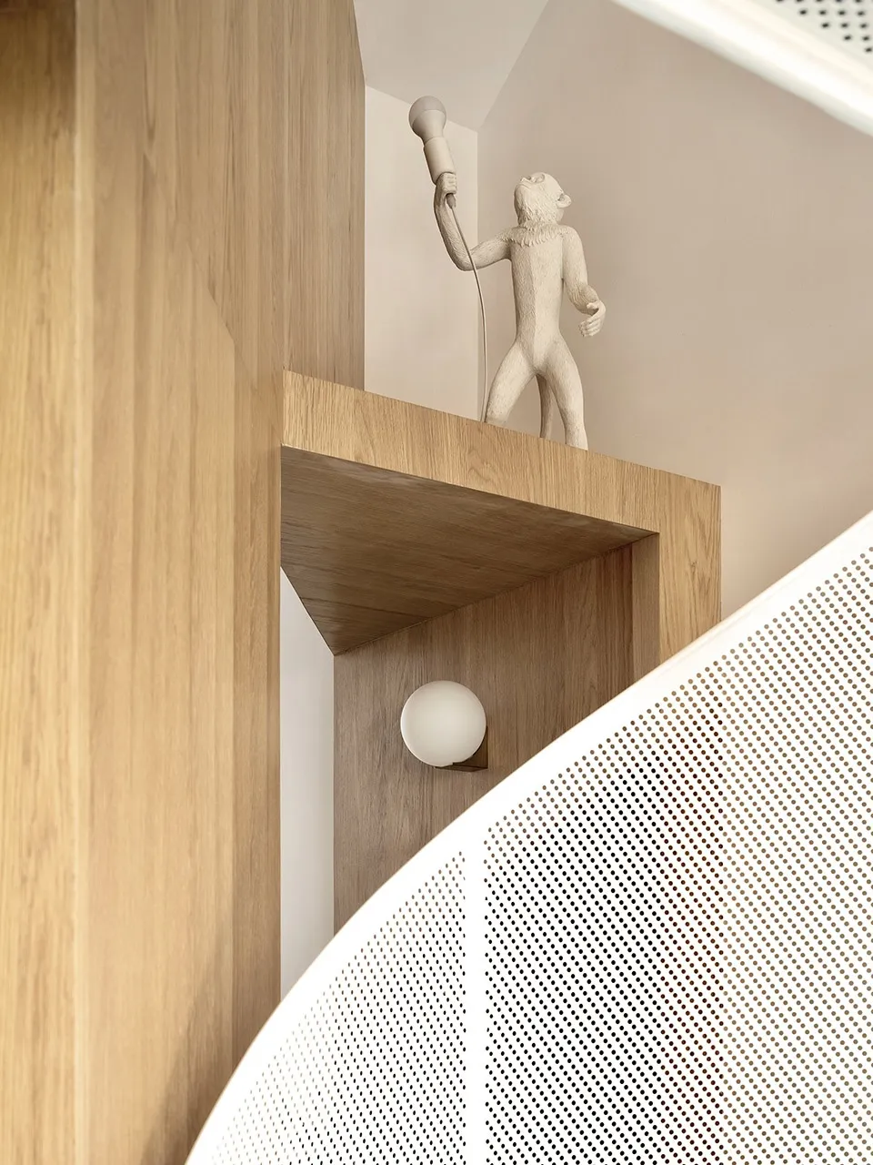 Modern, minimalist interior design featuring a wooden shelf with a monkey-shaped light fixture.
