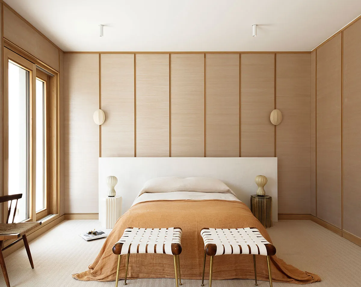 A modern bedroom featuring wooden paneling, a white bed with a wooden headboard, and beige bedding.