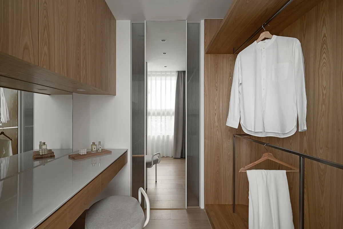 A modern clothing closet with wooden walls and a white dress shirt hanging on a wooden hanger.