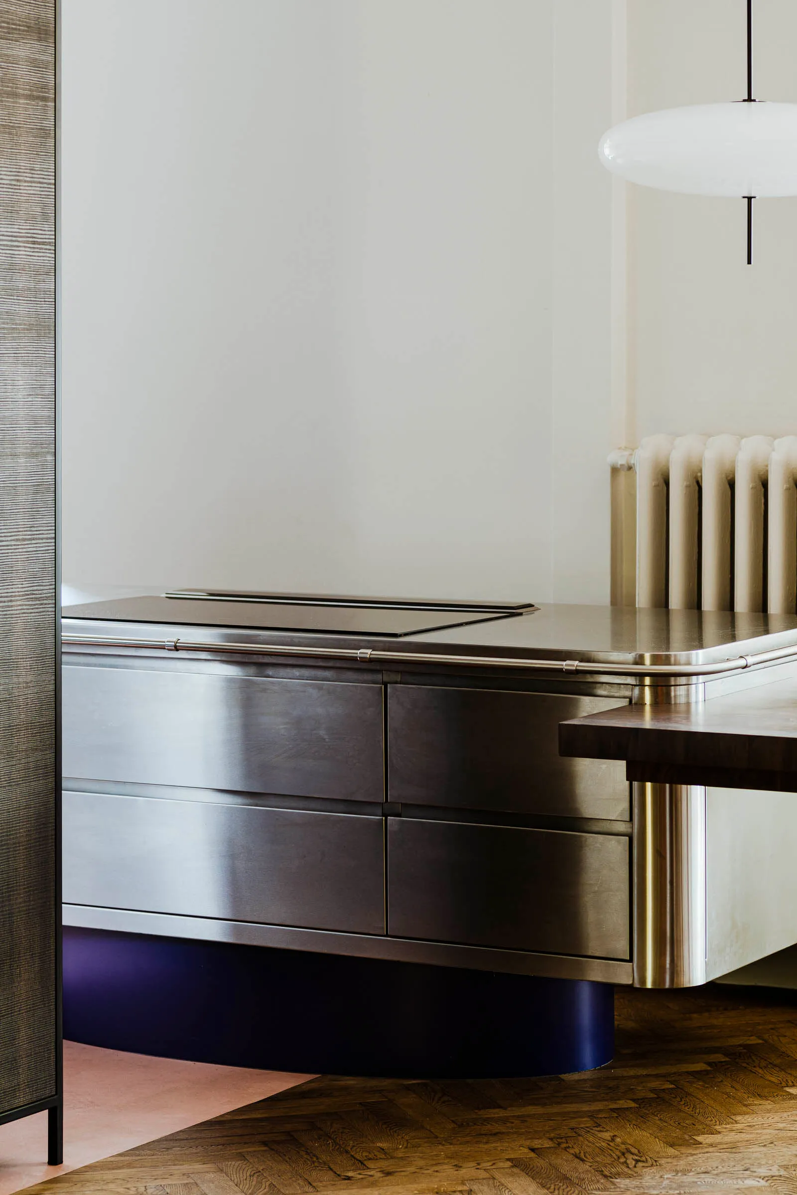 A minimalist interior with a metallic counter featuring sleek drawers and a smooth, curved base.