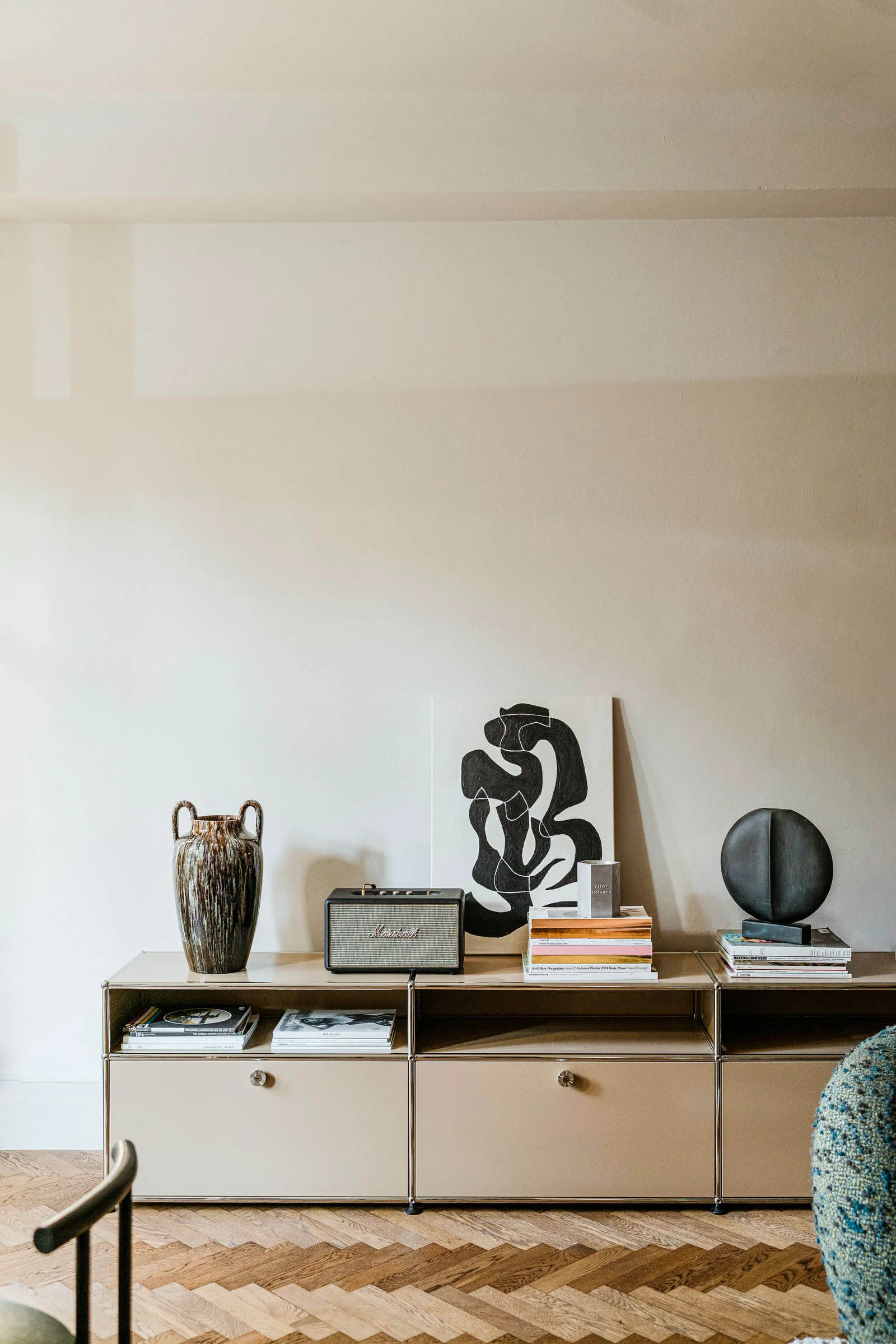 A modern living room featuring metal and wood furniture with abstract artwork and books.