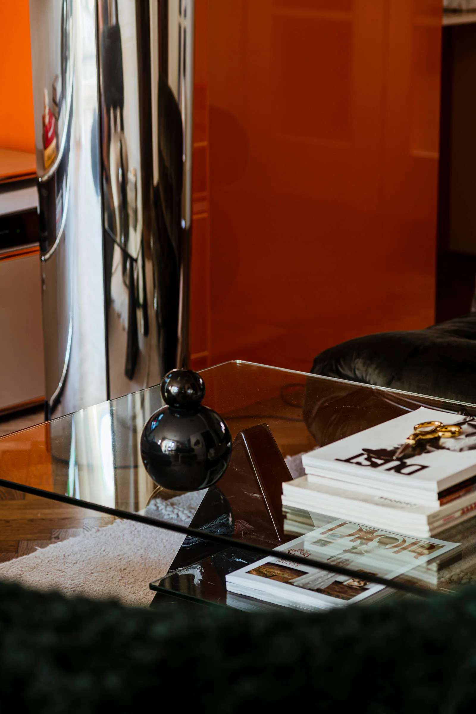 A modern coffee table with glass top and marble base, featuring decorative items and books.
