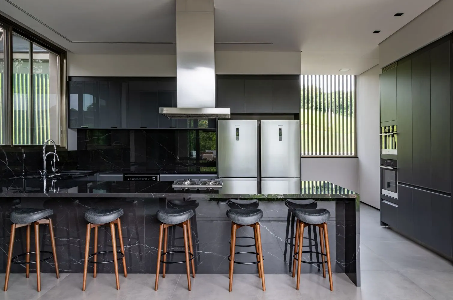 Modern kitchen featuring minimalist design, black marble countertops, and stainless steel appliances.