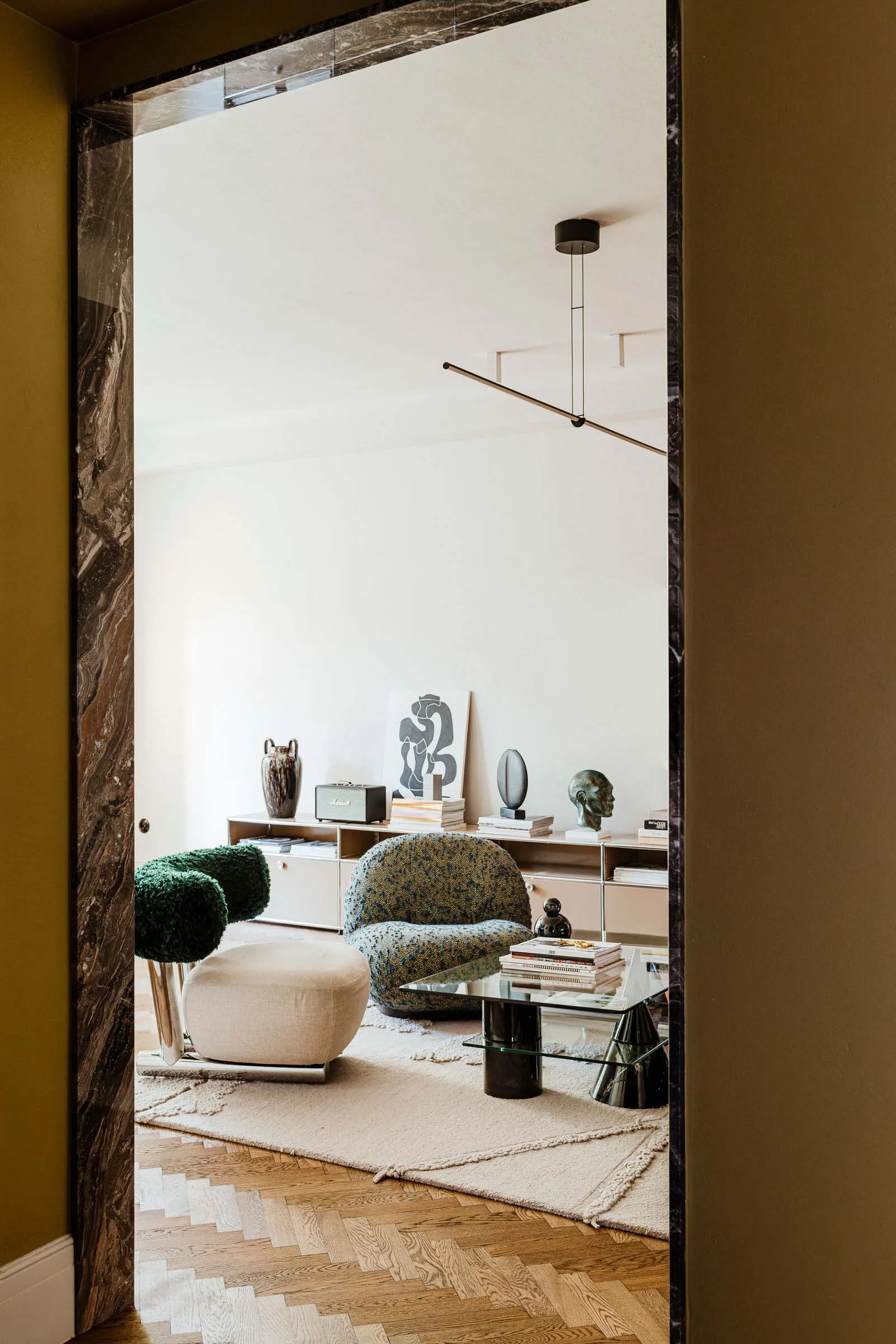 Modern living room with neutral-toned hardwood flooring, glass coffee table, and contemporary furniture.