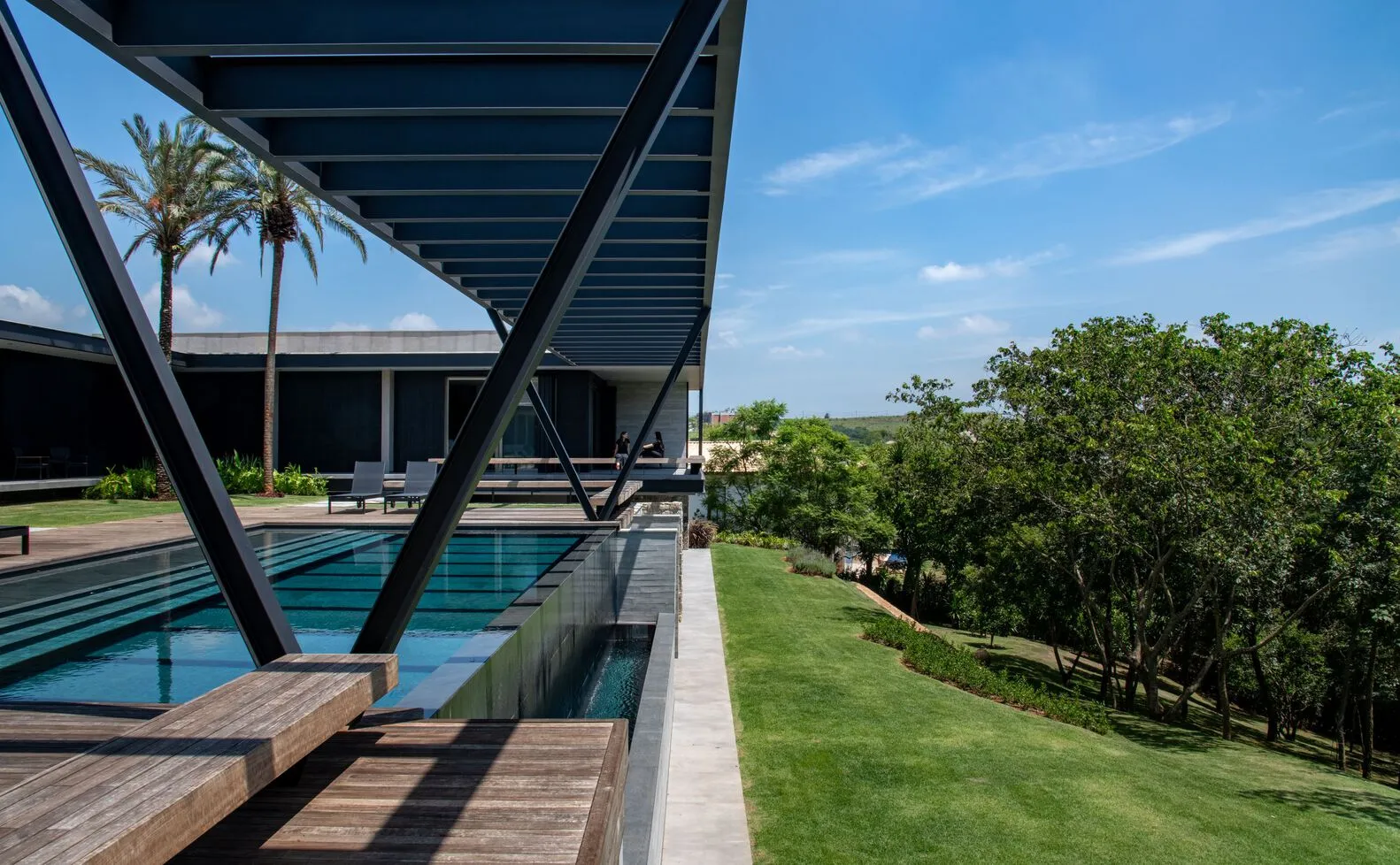 Modern metal structure with concrete swimming pool and landscape.