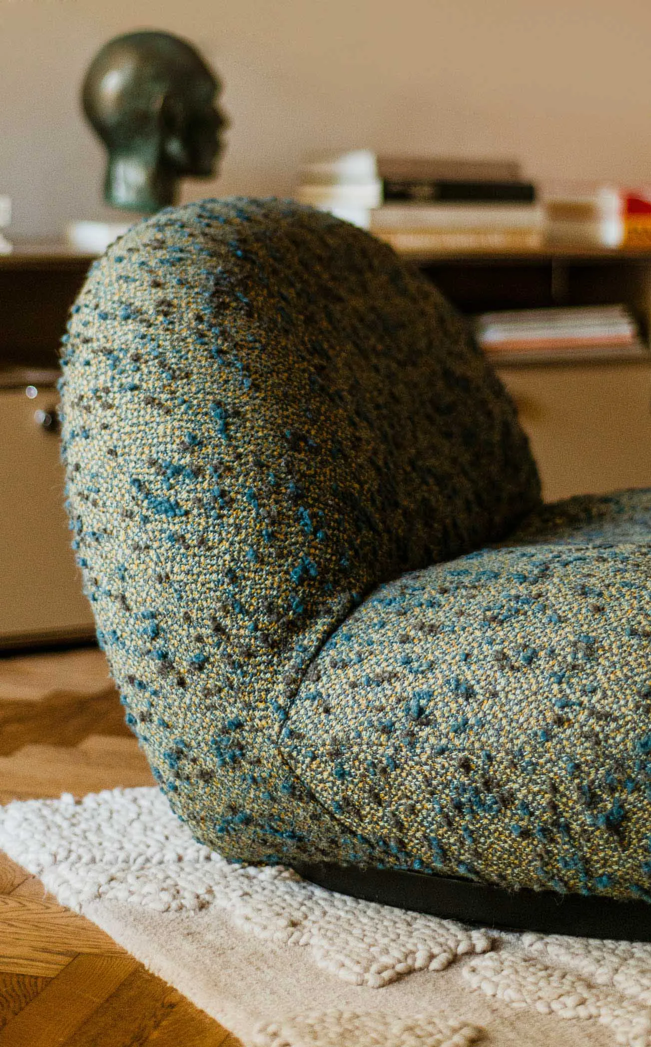 A modern sofa with a blue tweed fabric upholstery, placed on a white rug.