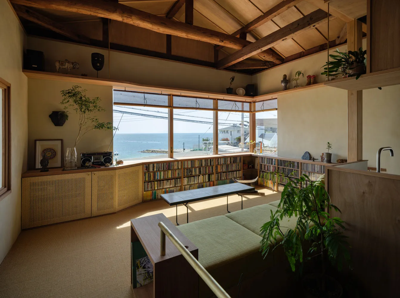 現代客廳以木質家具、玻璃隔屏與地毯鋪陳，透過大窗可眺望海景。