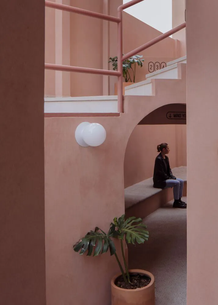 A minimalist interior space with a staircase featuring a combination of terracotta and concrete material finishes, with a per