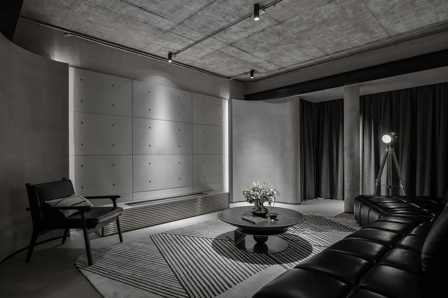 A stylish industrial living room with concrete walls and modern lighting features.