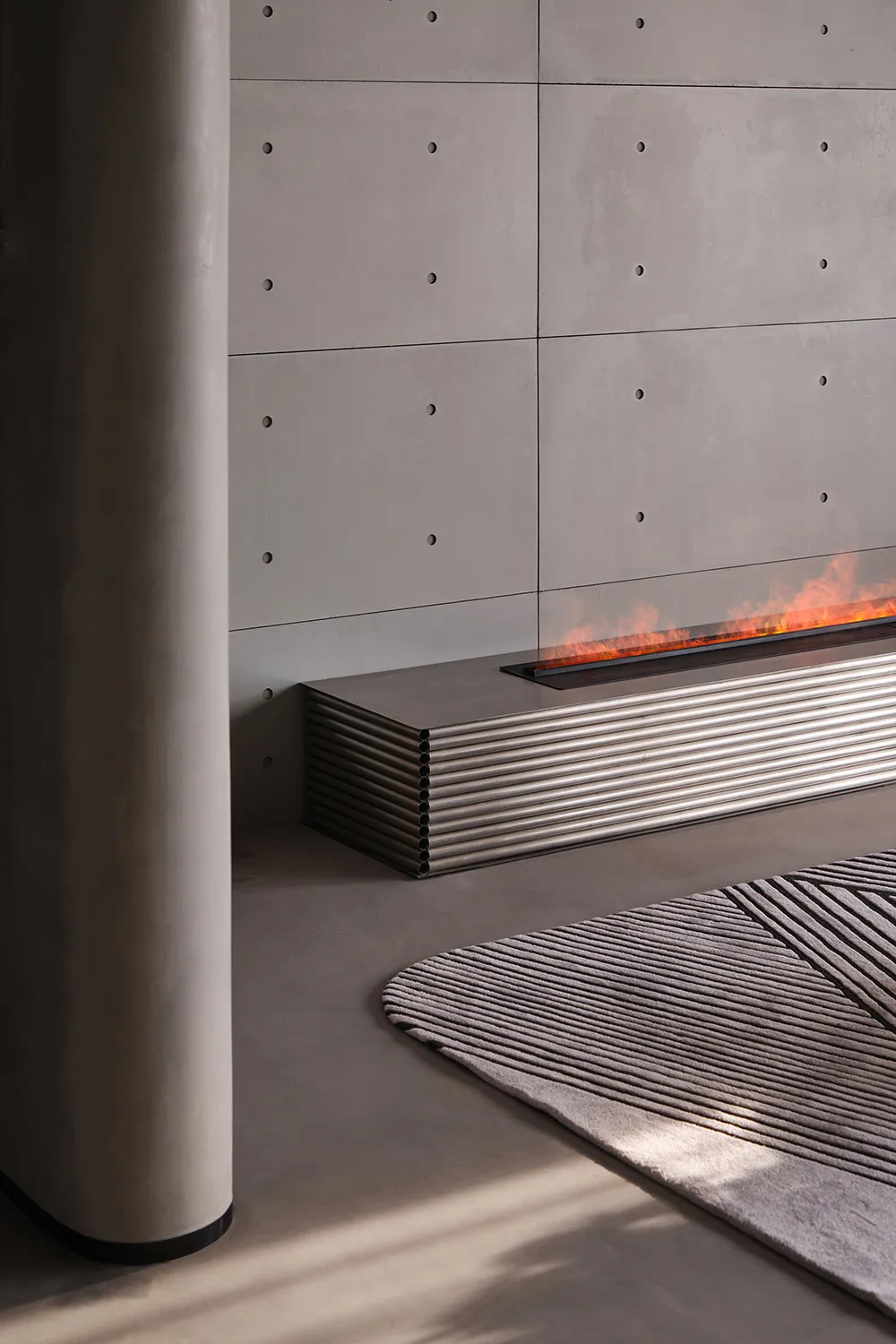 A modern fireplace featuring a concrete wall and steel accents.