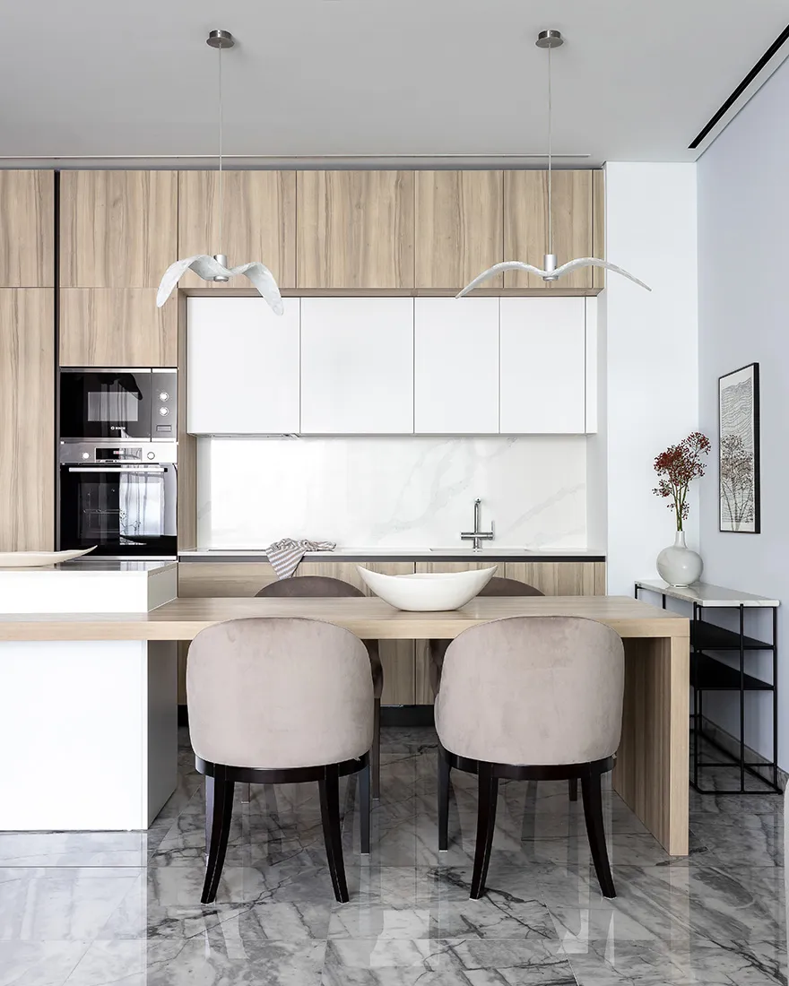 Modern kitchen with marble countertops and white wooden cabinets and table.