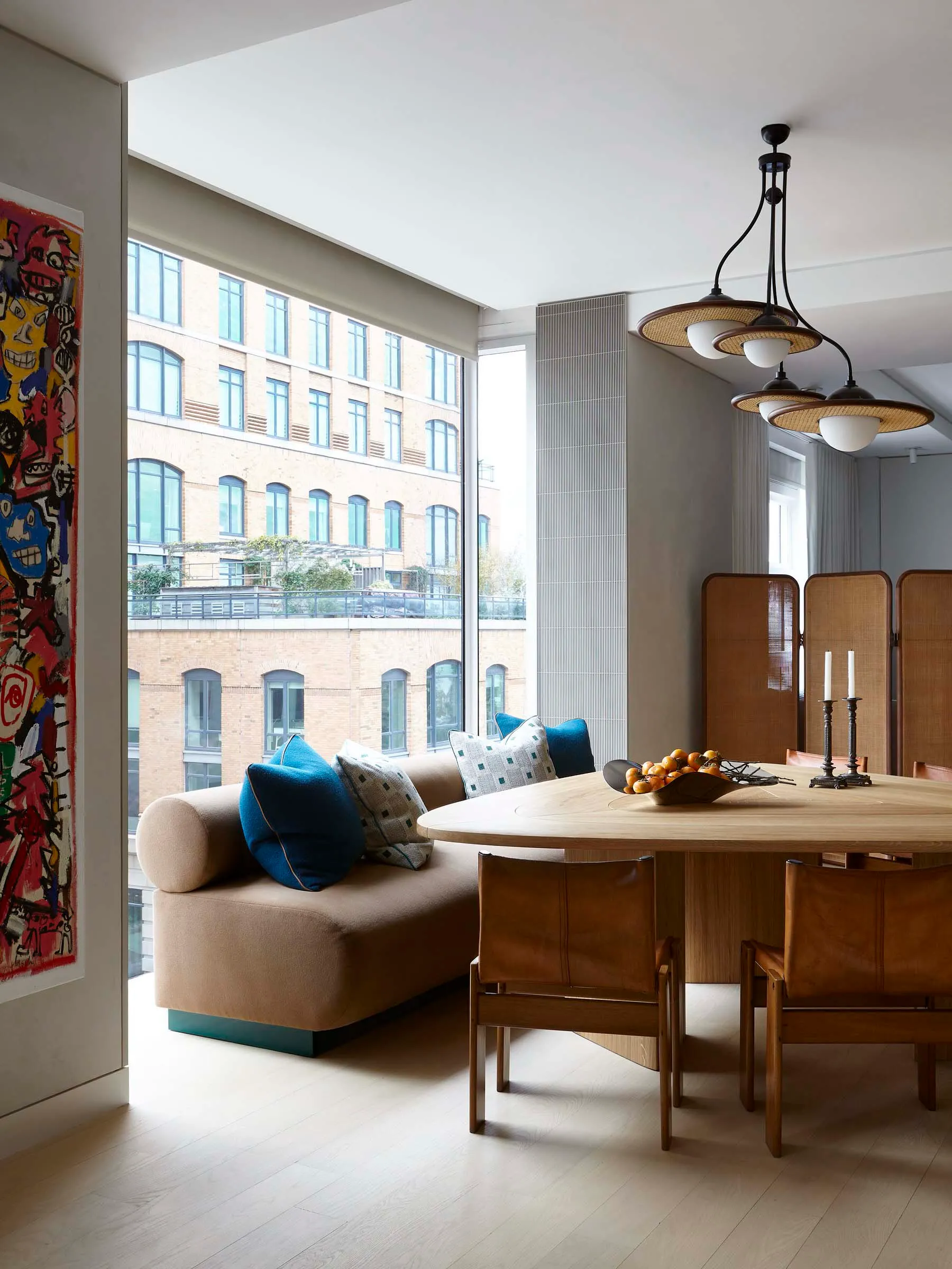 A modern living room with a cozy sofa adorned with cushions and a round wooden dining table surrounded by leather chairs, set