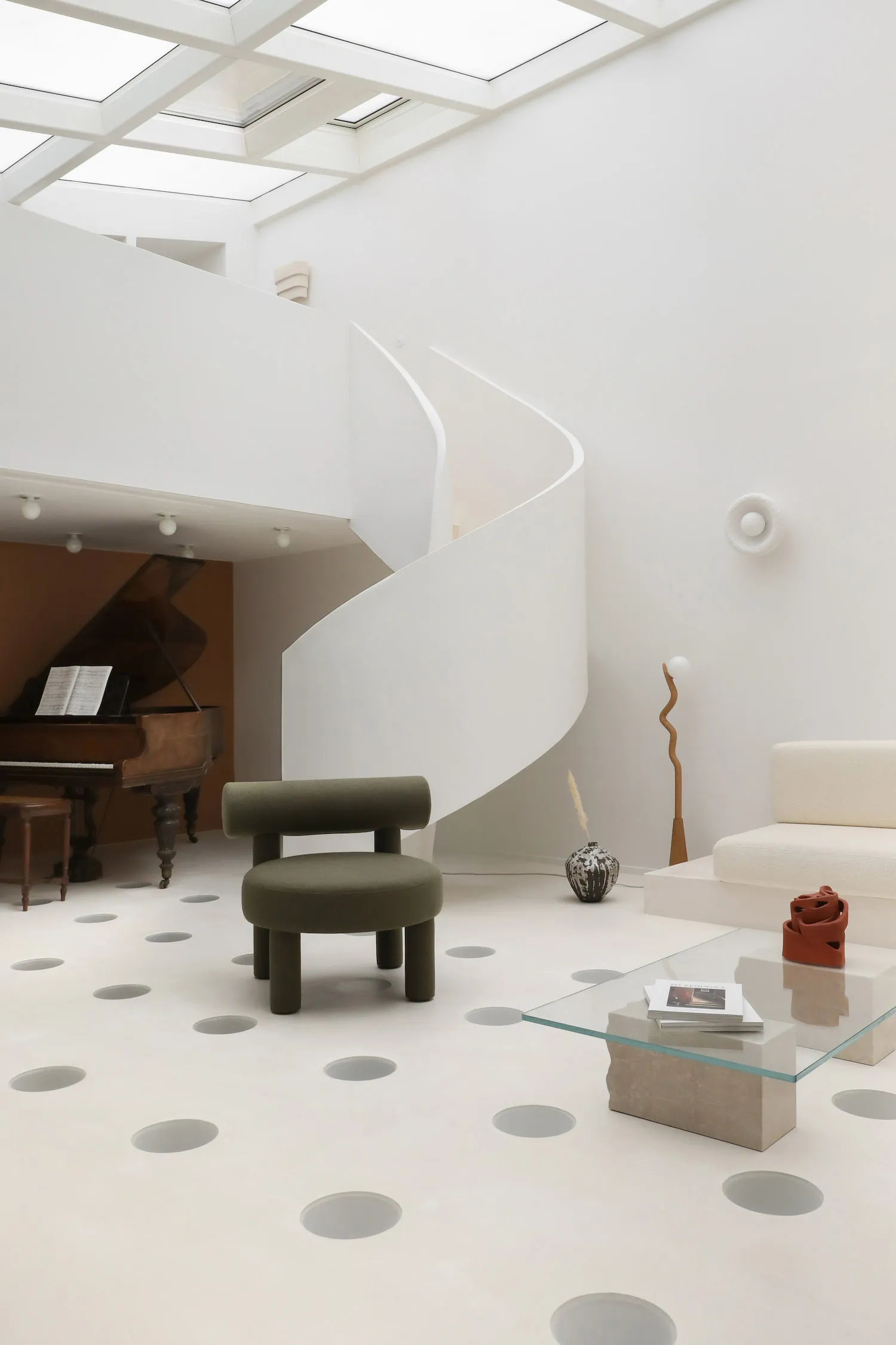 A minimalist interior space featuring a concrete floor with circular patterns and a spiral staircase.