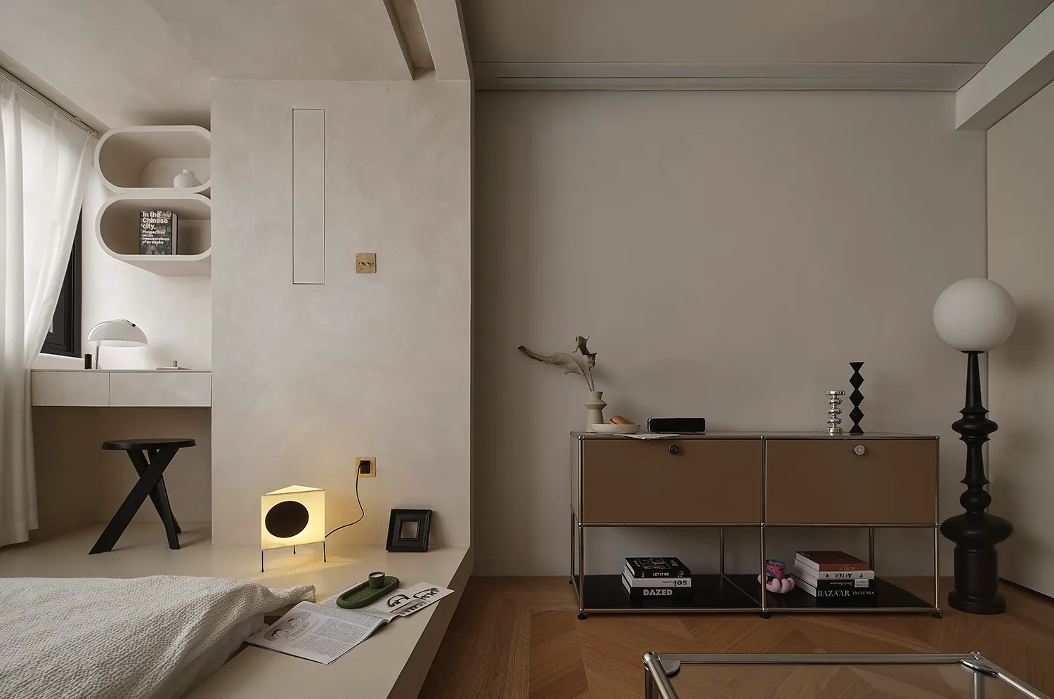 A modern, minimalist living room with concrete walls, a wooden floor, and a combination of white and brown furniture.