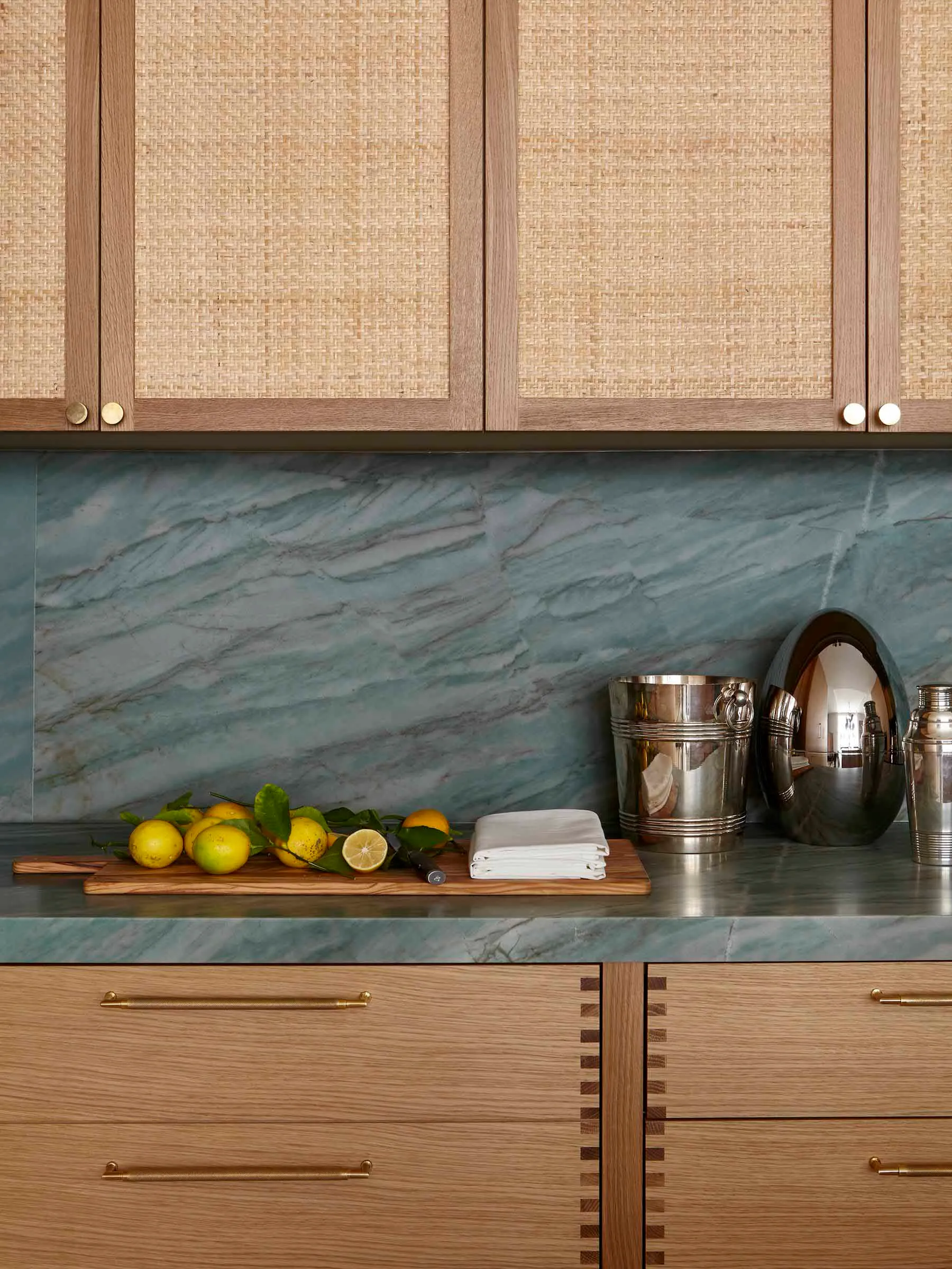A modern kitchen featuring a marble countertop, wooden cabinets, and metal decorative items.