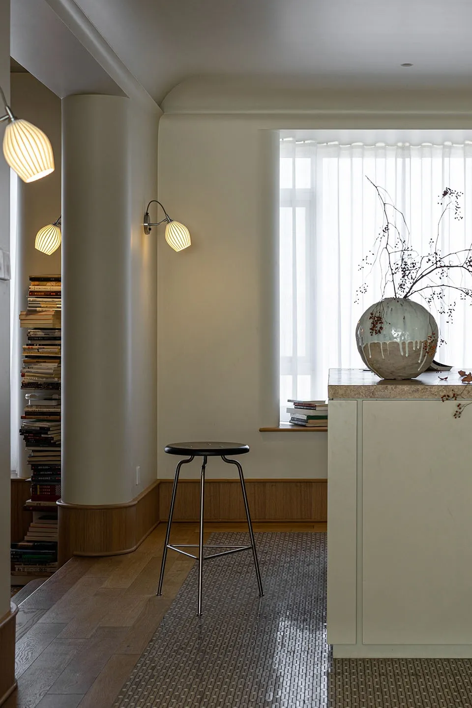 A modern apartment featuring minimalist design with wooden floors and a distinctive terrazzo counter, illuminated by warm sco