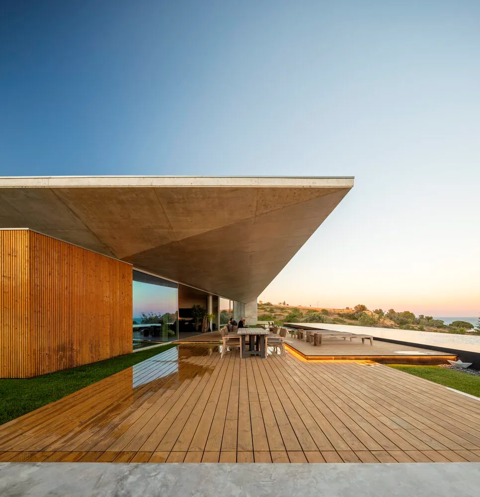 Modern architectural exterior featuring wooden and concrete elements with a sloping roof.