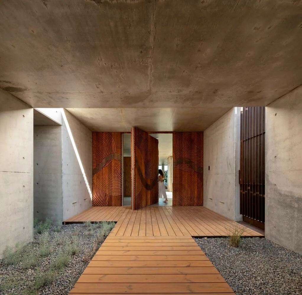 Modern architectural entrance featuring concrete walls and wooden flooring.