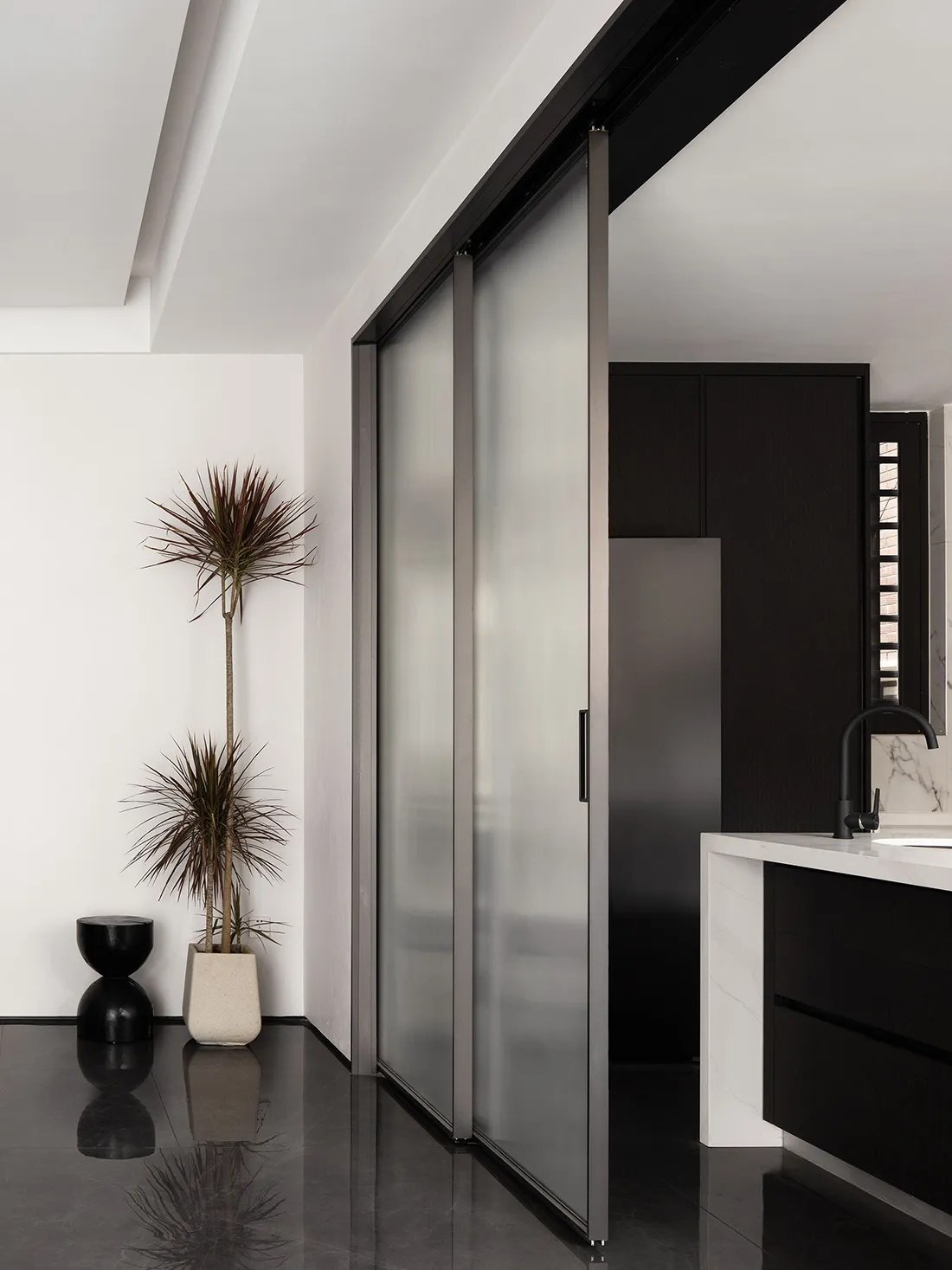 Modern residential interior featuring glass sliding doors and black accents.