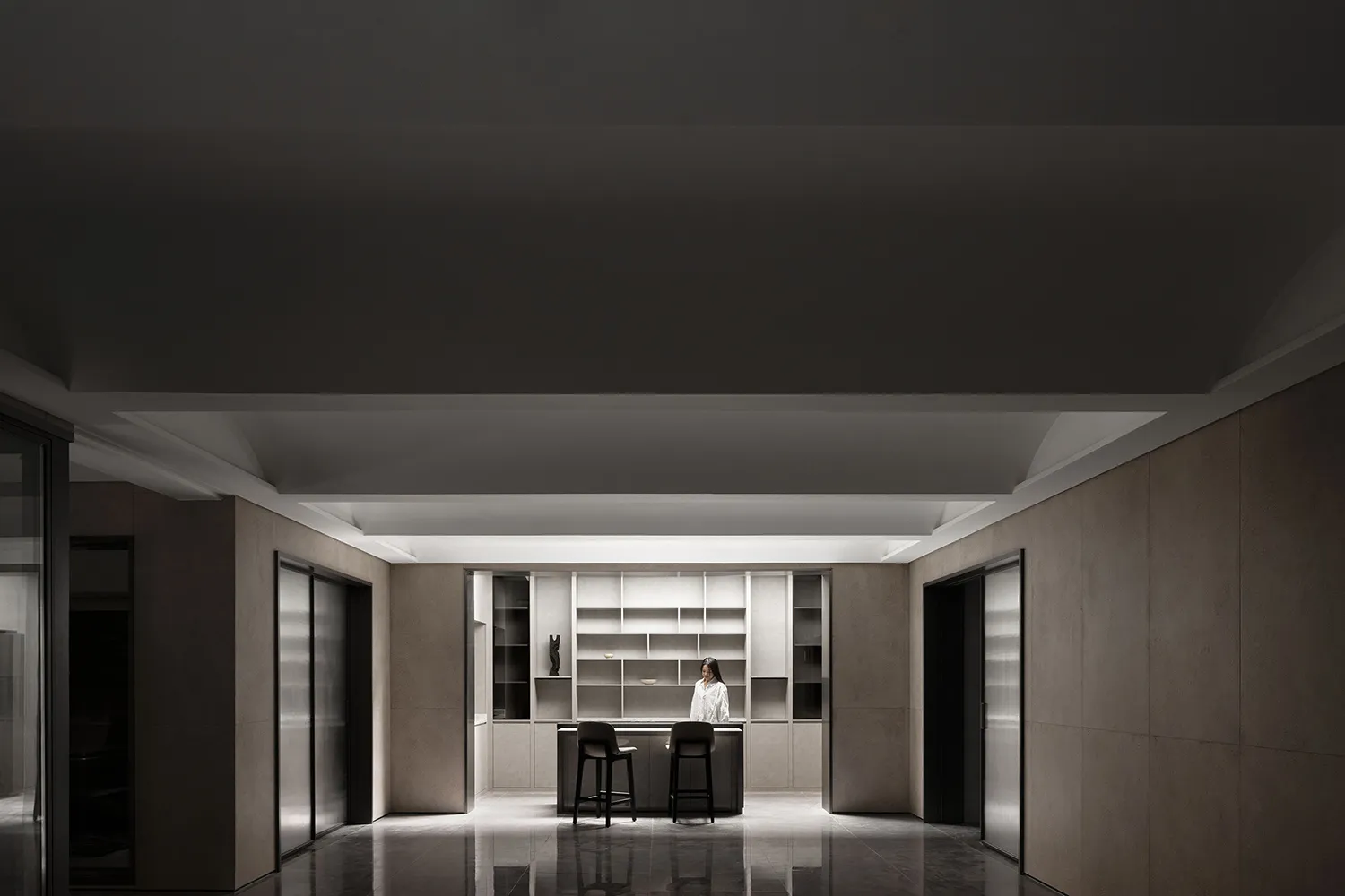 An interior space featuring a modern kitchen with minimalist design, including concrete walls and floor, and a sleek, functio