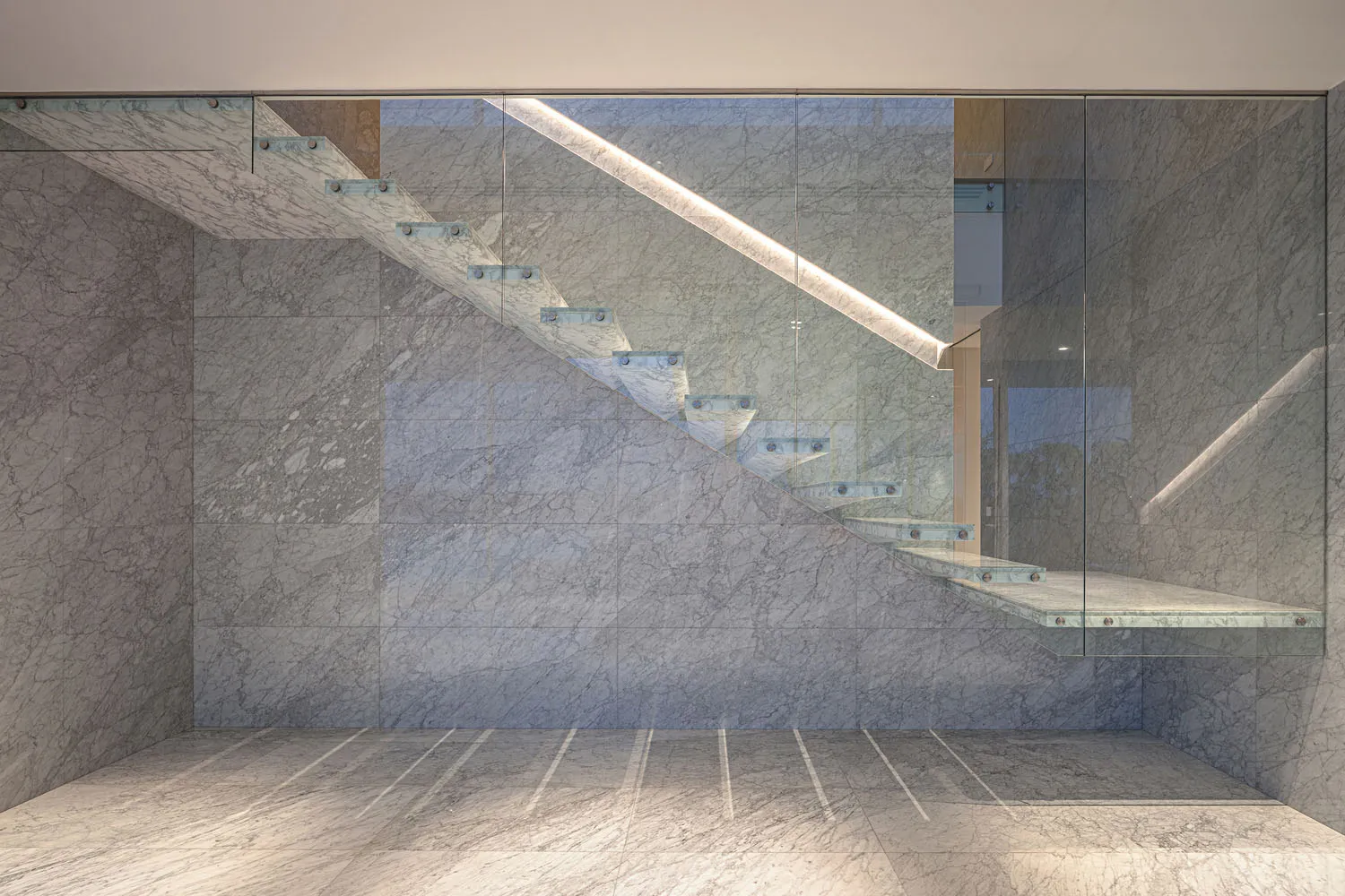 A contemporary interior design with marble elements, featuring a staircase and a minimalist aesthetic.