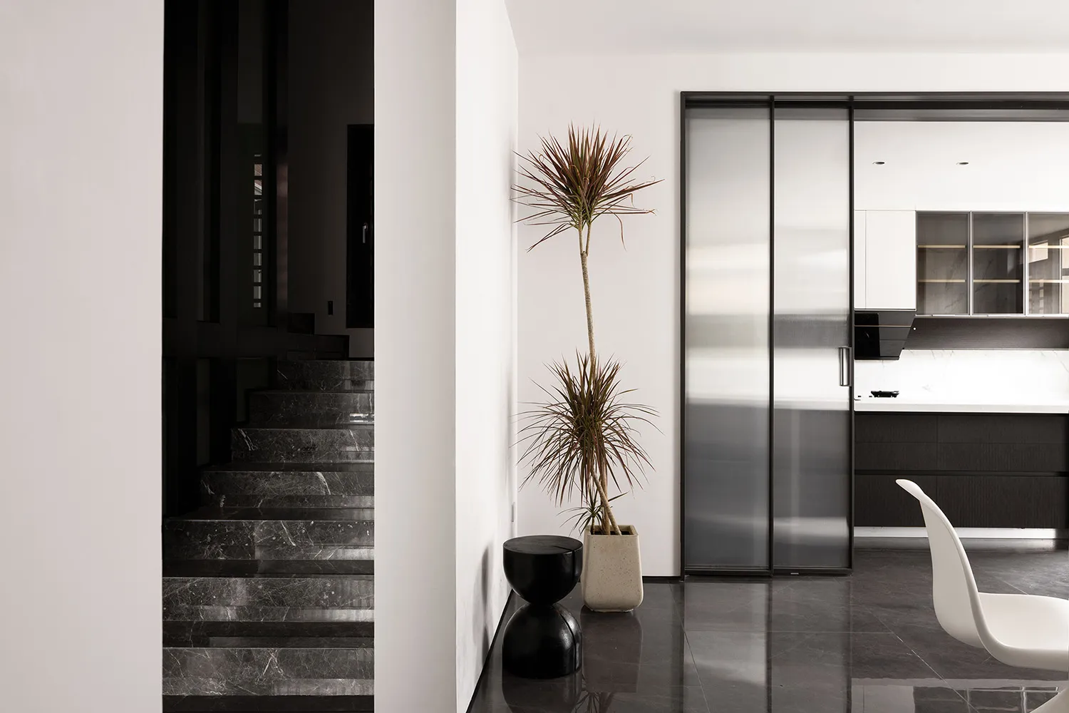 Modern kitchen with black marble countertops and black marble stairs, featuring sleek stainless steel appliances and a minima