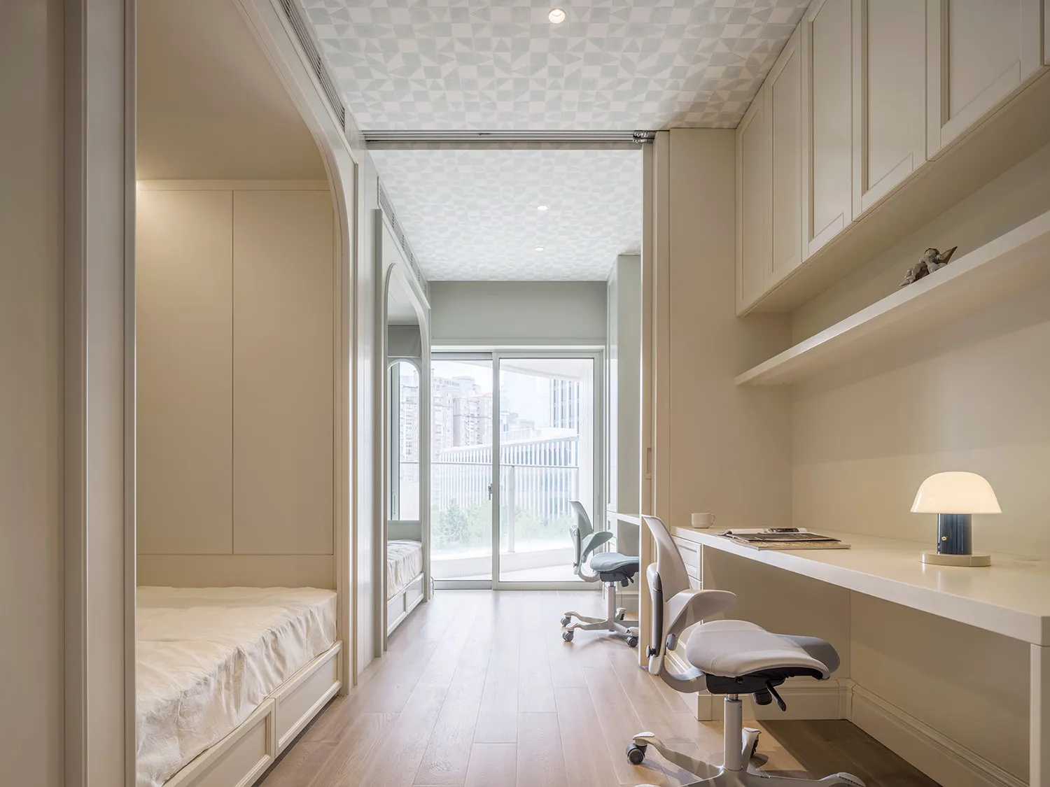 A modern minimalist office and bedroom with white furnishings and patterned ceiling.