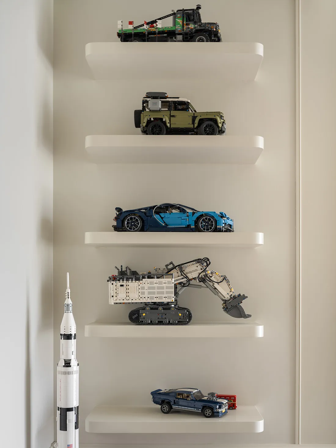 五個白色懸浮層架展示各種玩具車輛與一枚模型火箭。