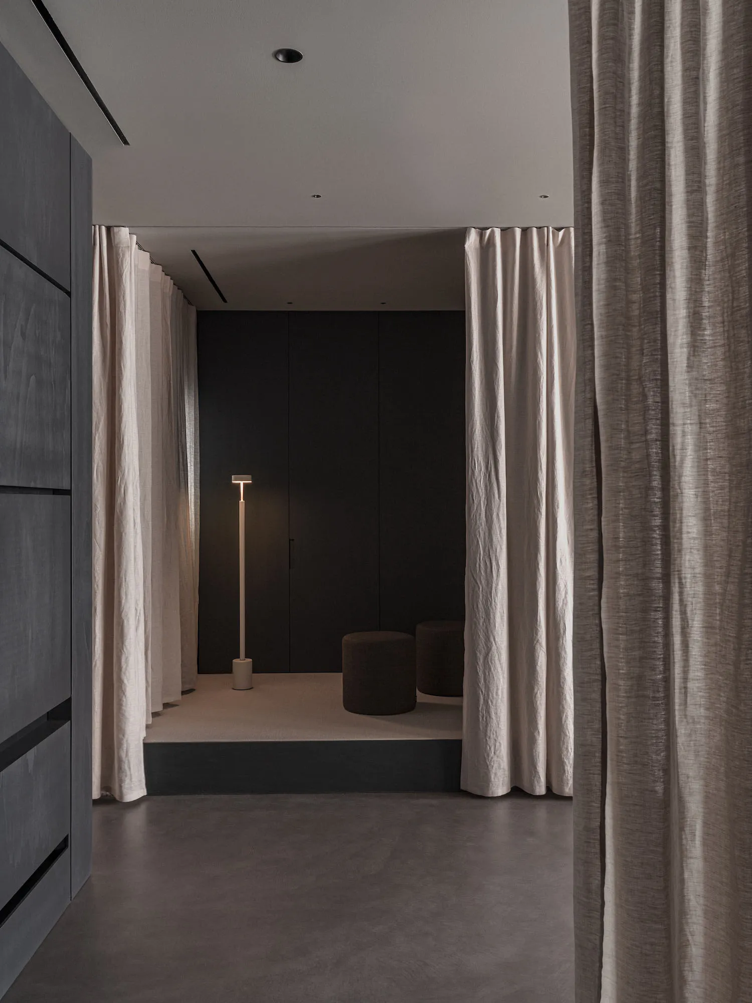 A minimalist living space with neutral-toned textiles and a sleek, modern floor lamp.