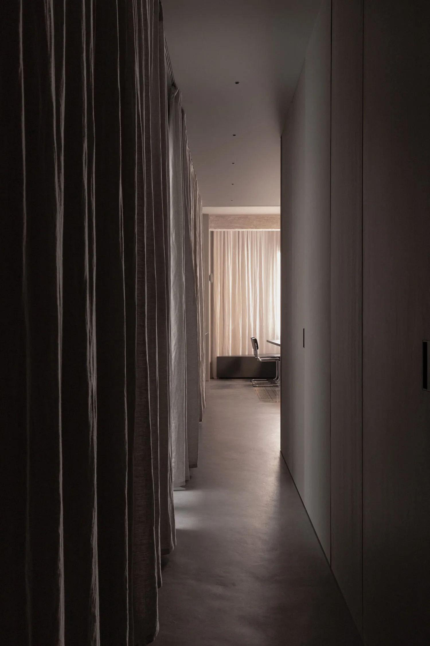 A modern corridor with fabric curtains leading to a well-lit area.