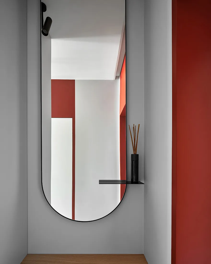 Modern entryway with a sleek, geometric mirror and a minimalist shelf.