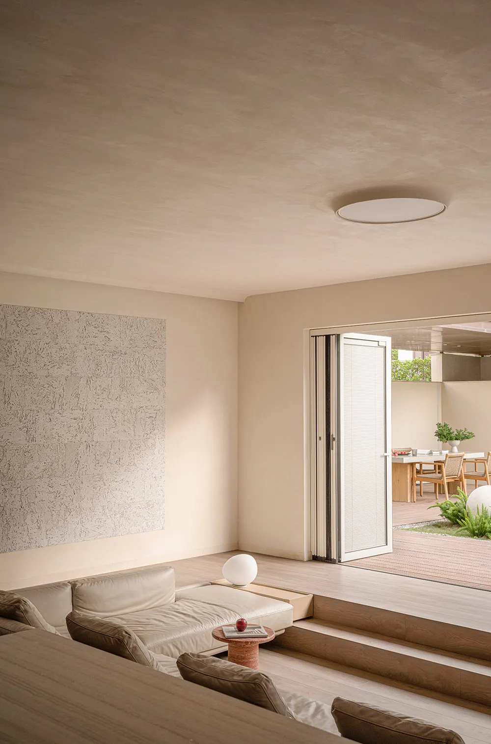 A modern living room featuring a wooden flooring, a white leather sofa, and a minimalist design with natural light.
