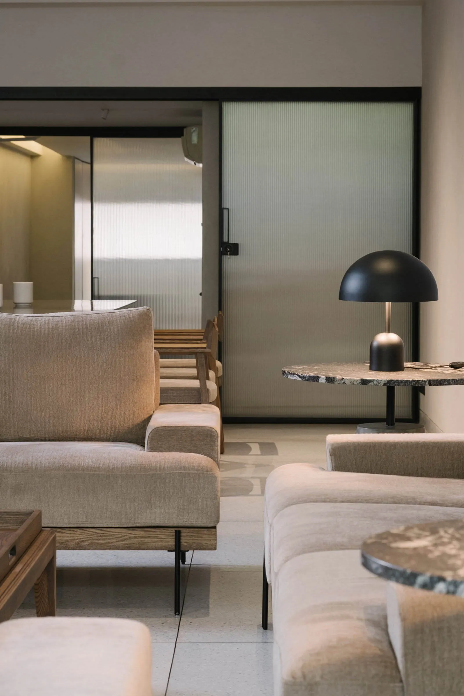 Modern interior with neutral fabrics, marble table, and black lamp.