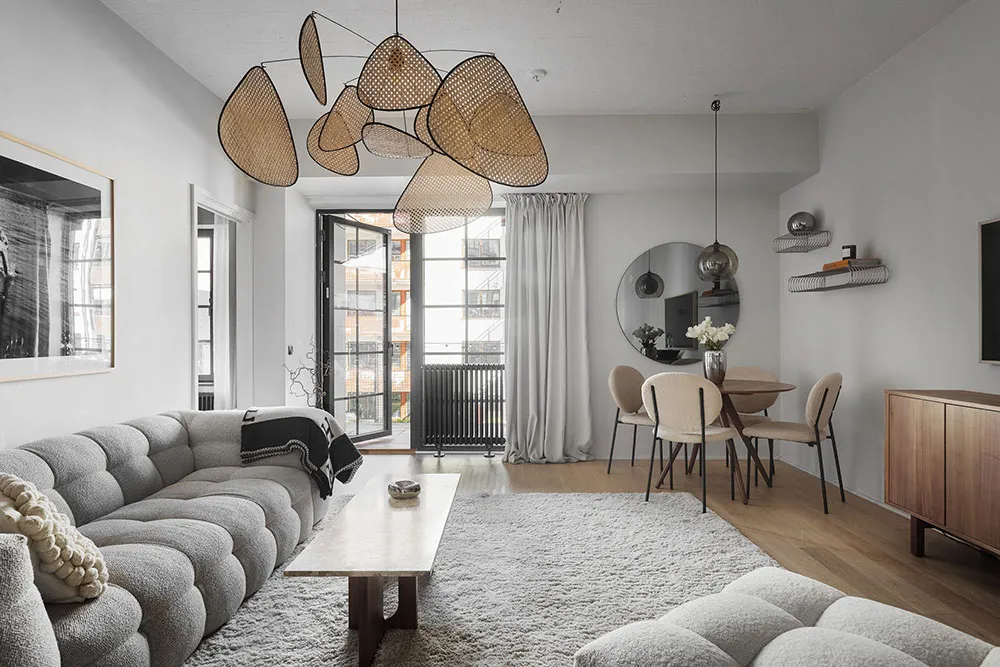 Modern living room featuring plush upholstered furniture, a cozy white rug, unique rattan pendant lights, and a comfortable r