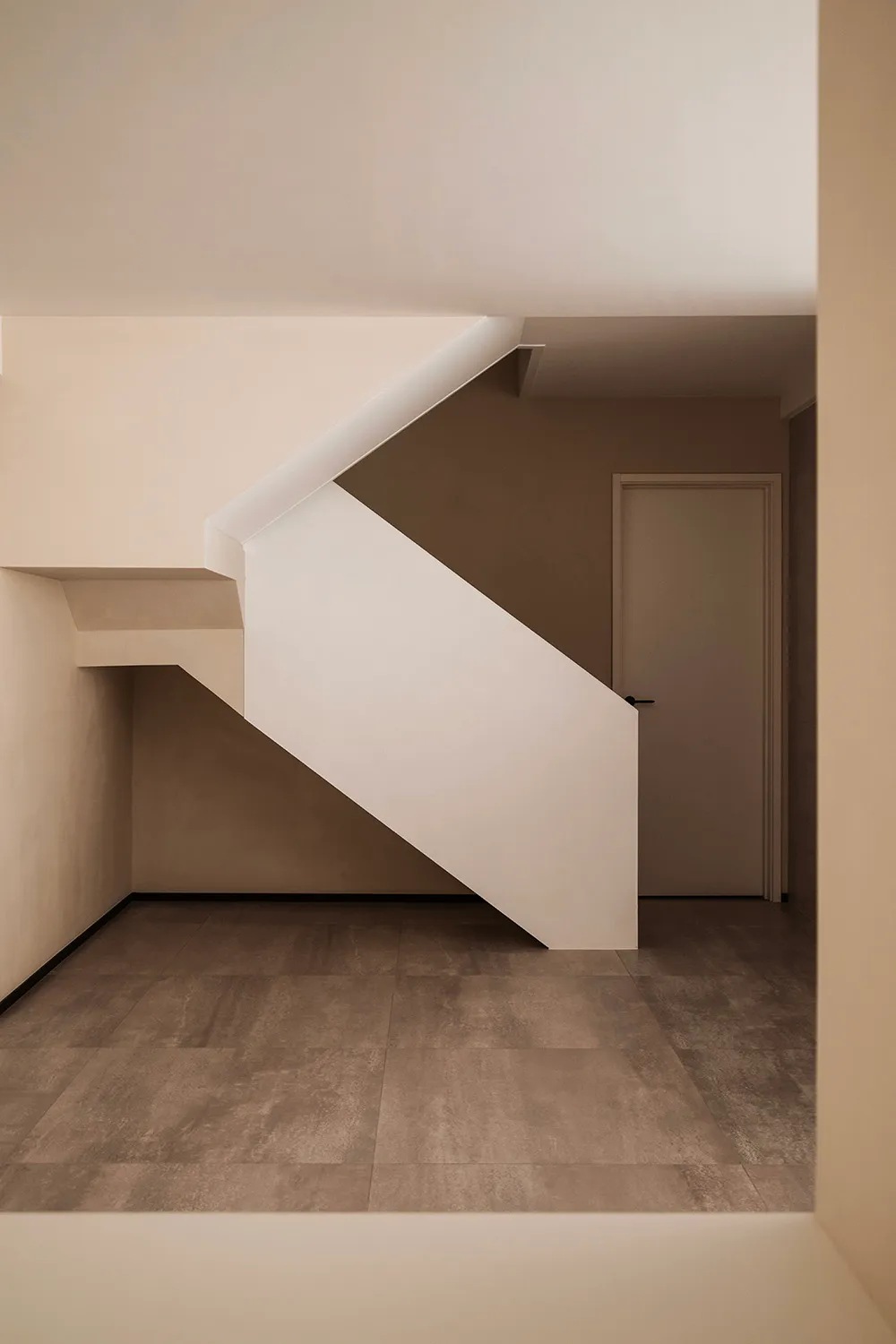 A minimalist interior design featuring a staircase with concrete tiles and a simple door.