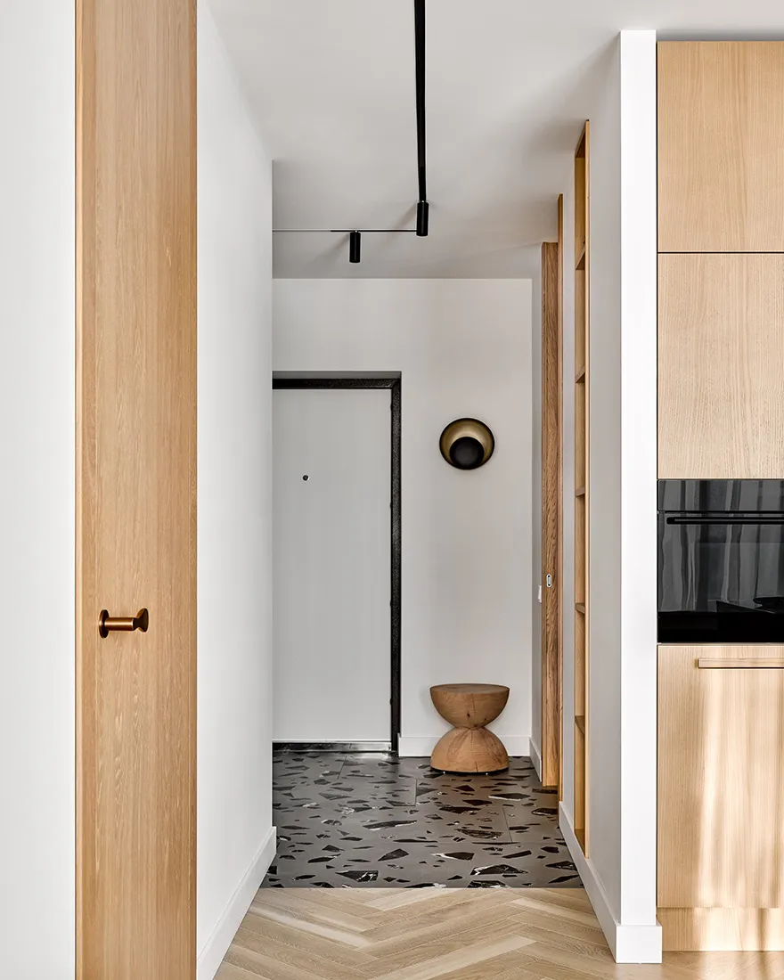 Modern kitchen featuring artistic black and white marble floor tiles with geometric patterns, wooden cabinets, and minimalist