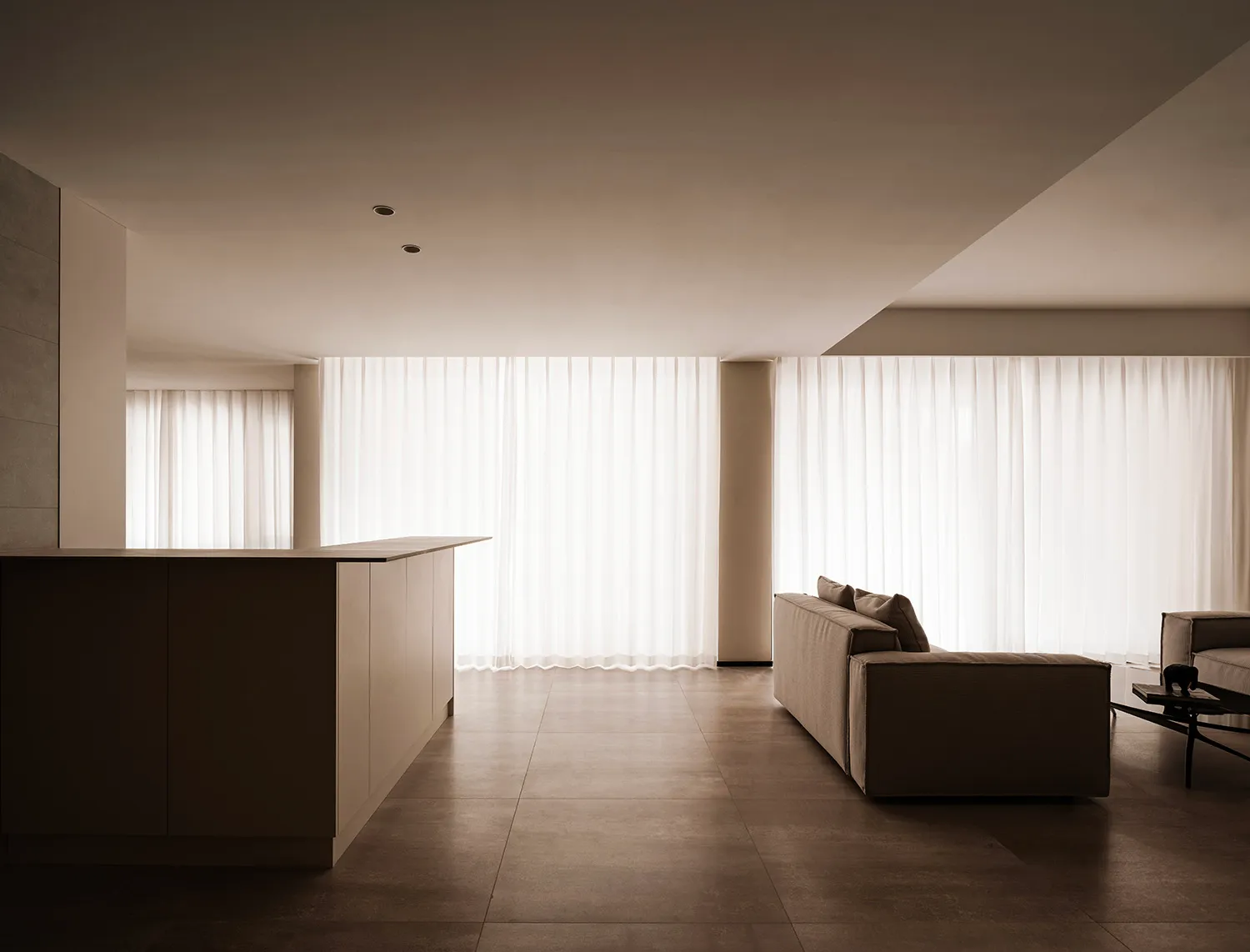 A minimalist living room with neutral-colored fabrics and a large window.