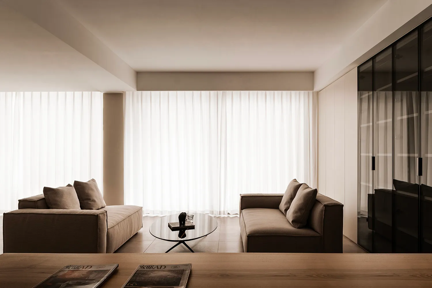 A minimalist living room featuring fabric sofas and a glass coffee table.