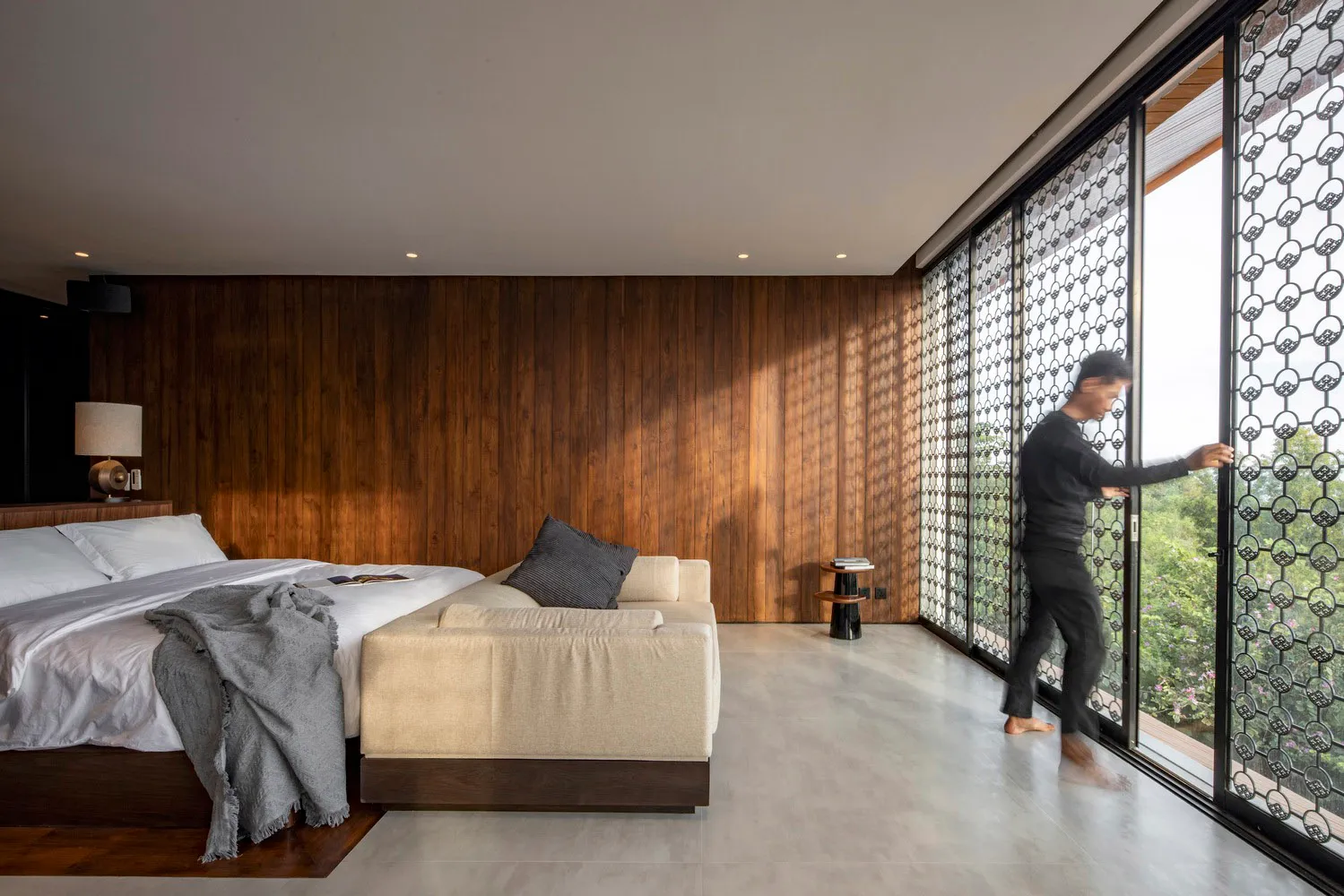 A modern bedroom featuring a comfortable bed and couch with white bedding and wood paneling.