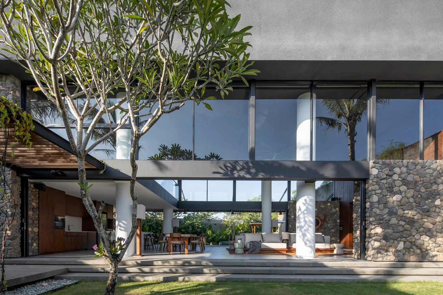 A modern residential interior featuring concrete, glass, and stone materials.