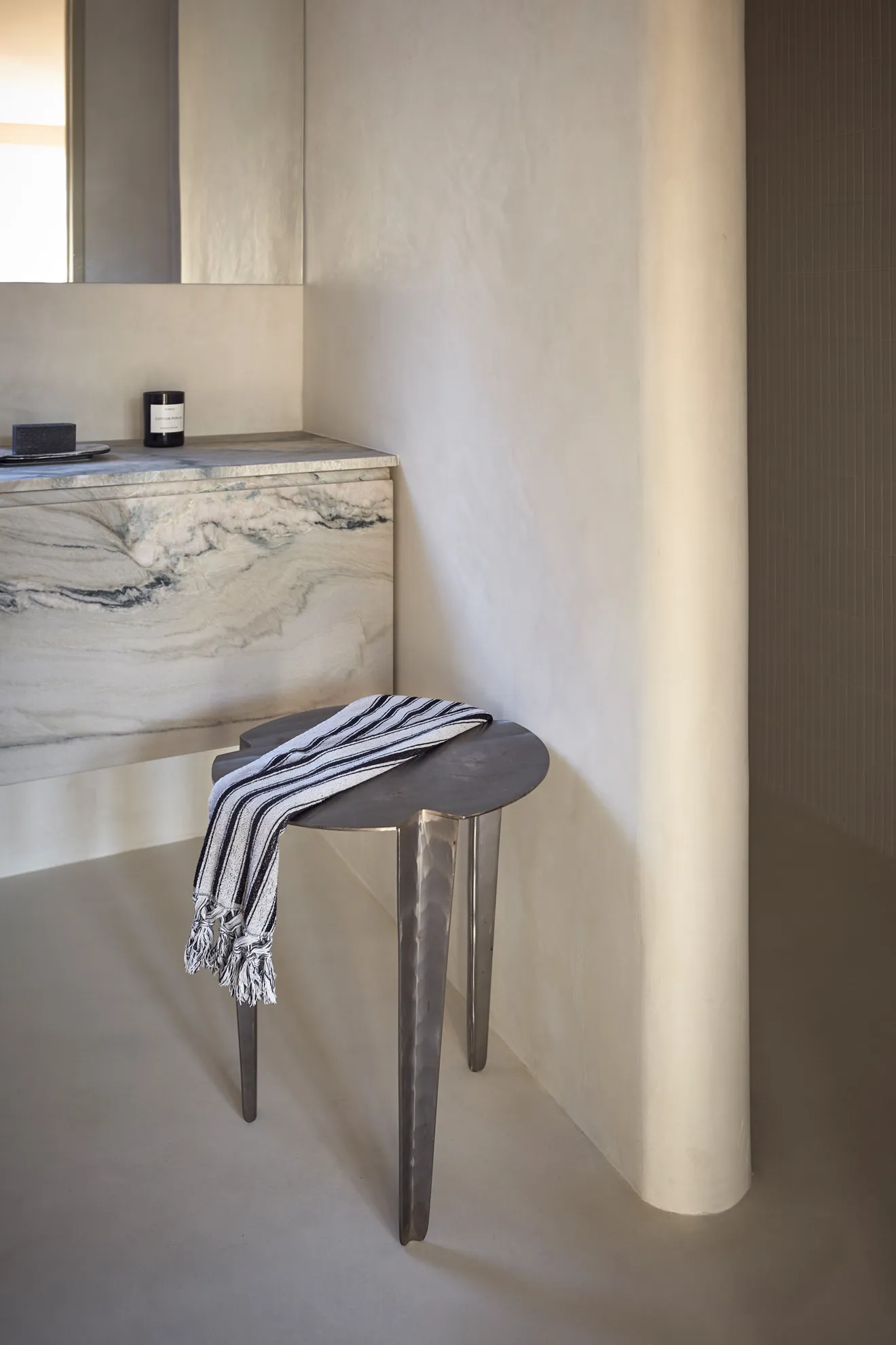 A minimalist bathroom with a marble countertop and stool.