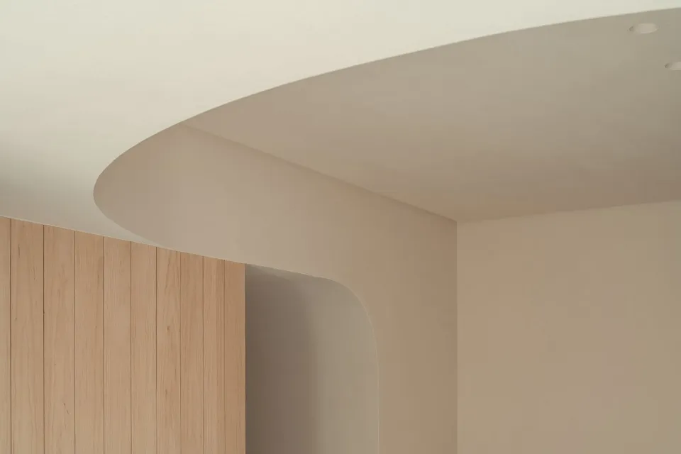 A modern interior design featuring a curved concrete ceiling and wooden paneling.
