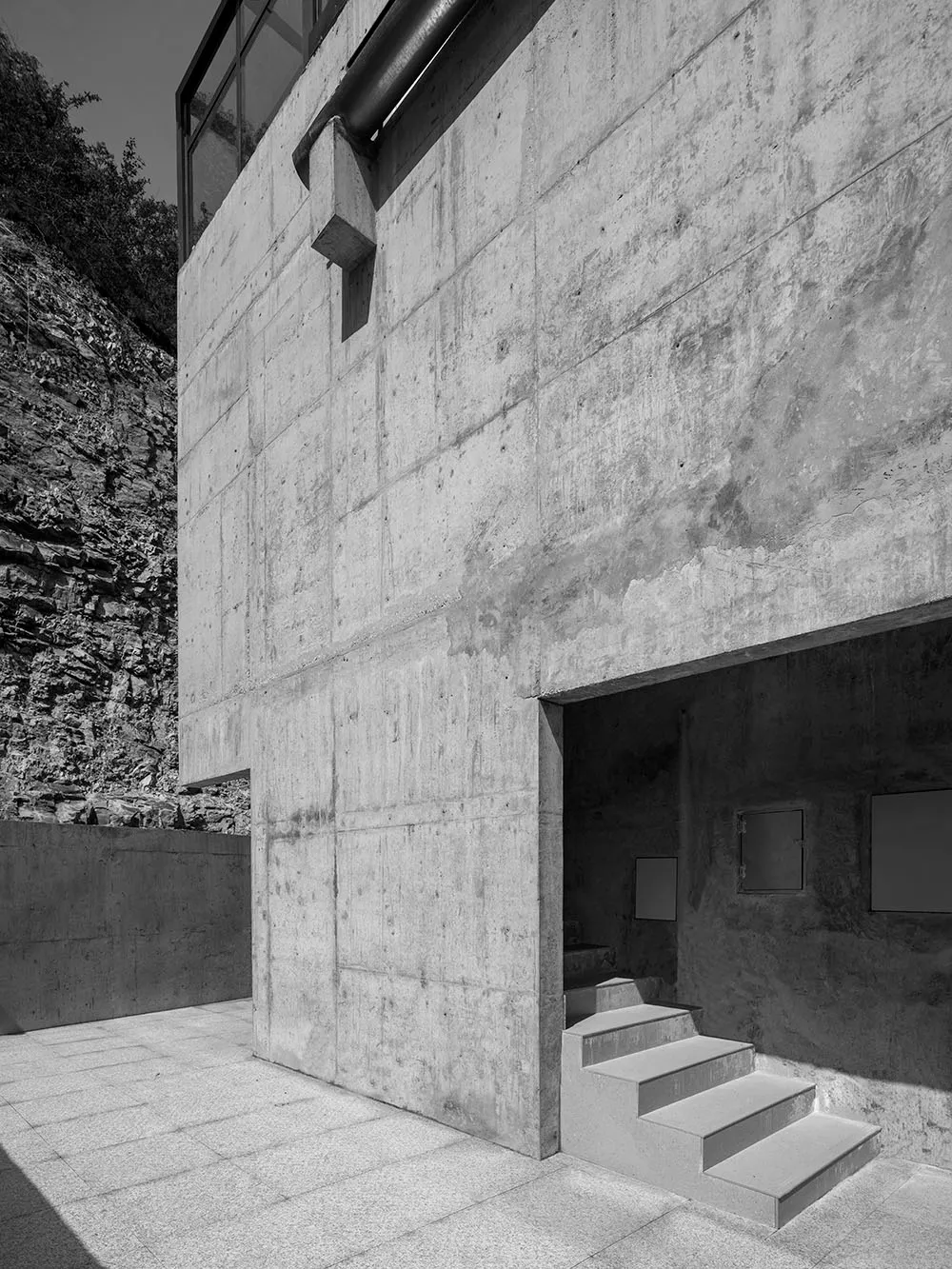 現代混凝土建築立面,階梯通往昏暗的室內空間。