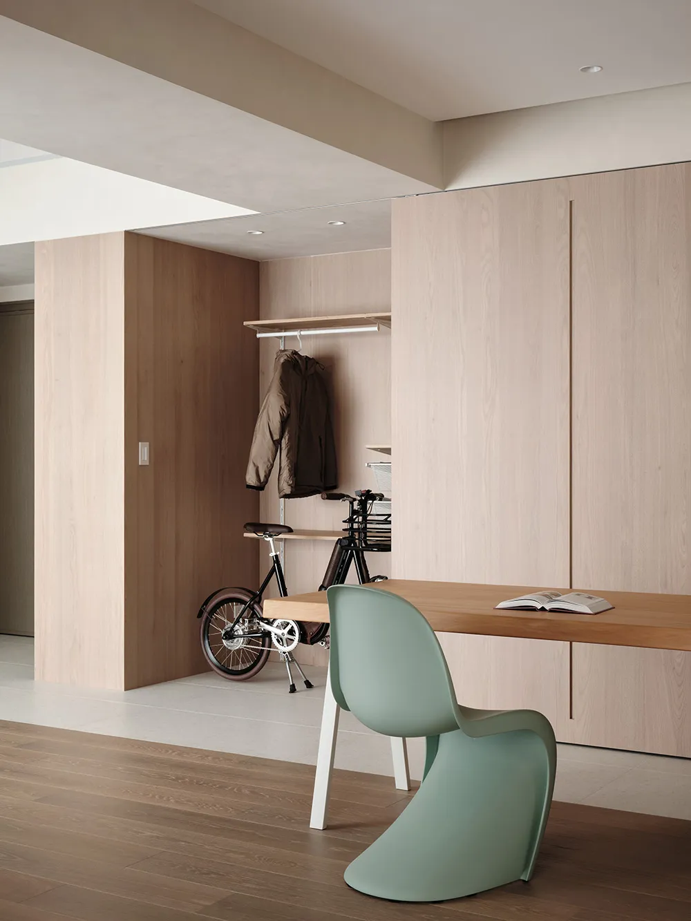 A modern home office featuring a wooden desk, a green chair, and a white wall.